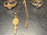 three gold rings and a necklace on a black surface