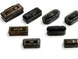 a lot of small black and gold tins on a white surface