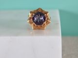 a close up of a gold ring with a purple stone in the center