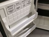 a person opening the door of a small black and white refrigerator