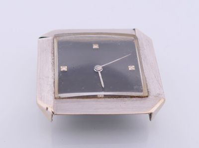 a silver watch with a black face sitting on a white surface