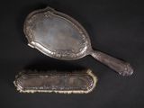 deux brosses à cheveux anciennes en métal argenté et un miroir sur fond noir