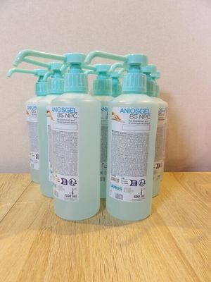 trois flacons de gel hydroalcoolique posés sur une table en bois