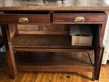a wooden table with a marble top and two drawers