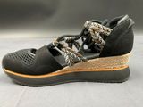 black and gold wedged sandals with braid straps on a gray surface