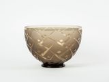 brown glass bowl with geometric design on black base on white background