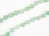 un gros plan sur un collier de perles de jade vert posé sur une surface blanche