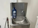 a stainless steel sink in a bathroom with a soap dispenser on the wall