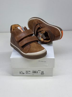 des chaussures de bébé en cuir marron avec des bandes Velcro, posées sur une boîte blanche