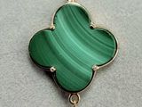 a close up of a bracelet with a green flower on it