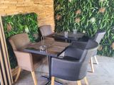a table and chairs in front of a wall of plants