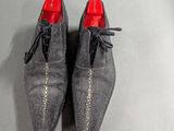men ' s grey shoes with red soles on a gray surface