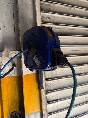 un tuyau bleu fixé au mur à côté de la porte de garage
