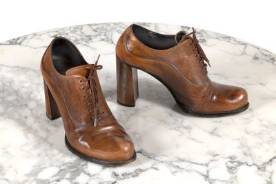 une paire de chaussures en cuir marron posée sur une table en marbre, sur fond blanc