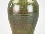 un vase vert posé sur une surface blanche
