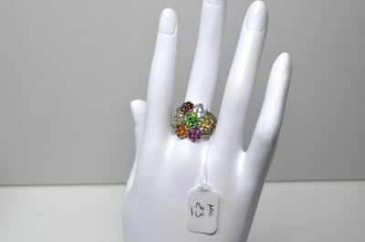 une main blanche ornée d'une bague sertie de pierres multicolores
