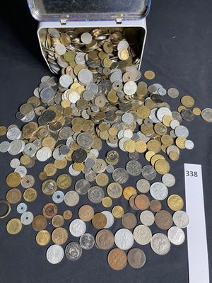 coins spilling out of a metal container on a table next to a ruler
