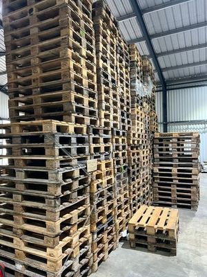 des palettes empilées dans un entrepôt, avec une fourche au premier plan