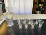 Des bouteilles et des verres sont alignés sur une table à côté d'une carafe.