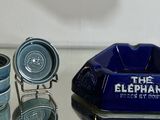 a blue elephant ashtray and four cups on a glass table