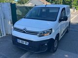une camionnette blanche garée sur un parking près d'une clôture