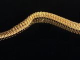 a gold bracelet on a black surface with a black background