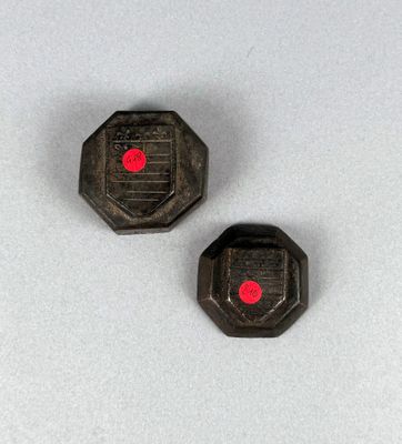 deux boutons en plastique noir et rouge posés sur une surface blanche