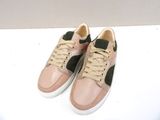 beige and green sneakers with laces on top of a white surface