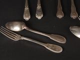 a lot of silver spoons and forks on a black table