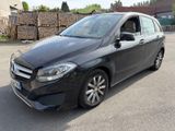 the mercedes b - class is parked in a parking lot in front of a pile of logs