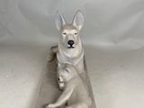 sculpture of a dog resting on a stone block with a white background