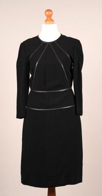 une robe noire posée sur un pied de mannequin, avec un mannequin blanc en arrière-plan