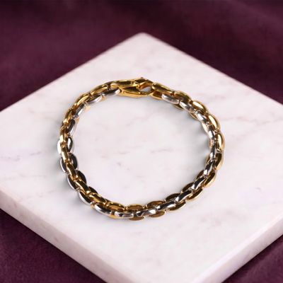 un gros plan d'un bracelet en or et en argent posé sur une surface en marbre