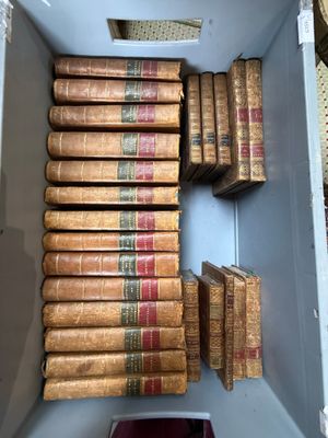 de nombreux livres anciens dans une boîte blanche posée par terre