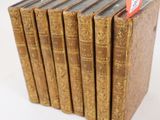 six vieux livres sont empilés sur une surface blanche