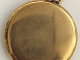 a close up of a gold pocket watch on a white surface