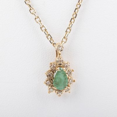 a close up of a necklace with a green stone on a chain