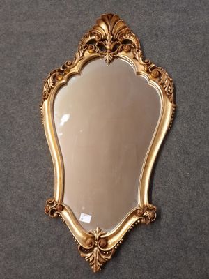 un miroir accroché au mur, avec un cadre doré