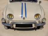 a white car with blue stripes parked on the side of the road