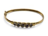 Gros plan sur un bracelet en or orné de pierres bleues