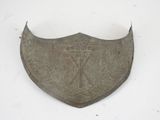 an old metal shield with a design on it on a white surface