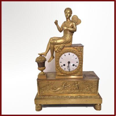 une horloge en or avec une femme assise dessus