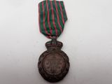 an old medal with a red and green ribbon on a white surface