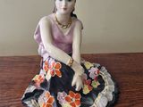 figurine of a woman sitting on top of a wooden table