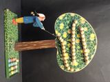 une figurine représentant un homme en train de couper une branche d'arbre avec un couteau
