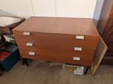 a wooden chest of drawers in the corner of a room