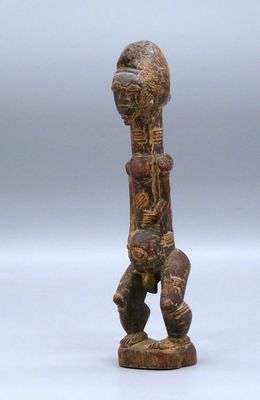 an old wooden figurine of a man sitting on a stool