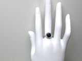 une main portant une bague, posée sur un mannequin