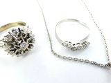 deux bagues, un collier et une bague posés sur une surface blanche