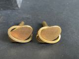 a pair of gold tone cufflinks with a curved design